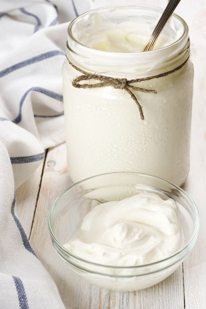 Yogurt in a jar on a wooden table. | MakeSauerkraut.com