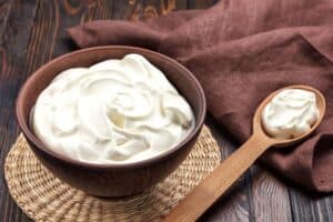 Sour cream in a wooden bowl on a mat.| MakeSauerkraut.com