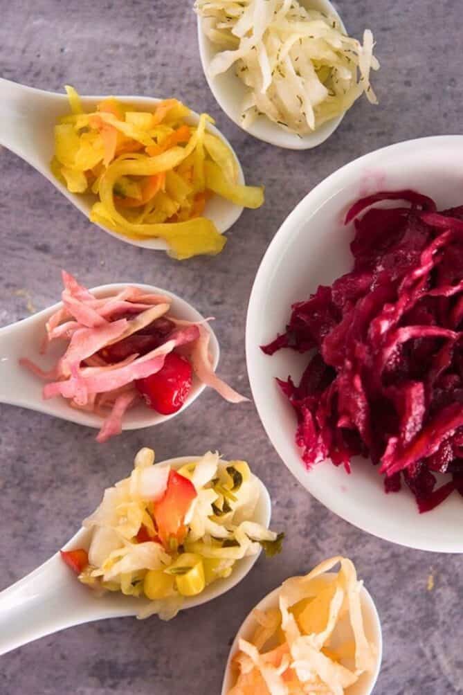 A bowl and five spoons of different sauerkraut flavors. | makesauerkraut.com